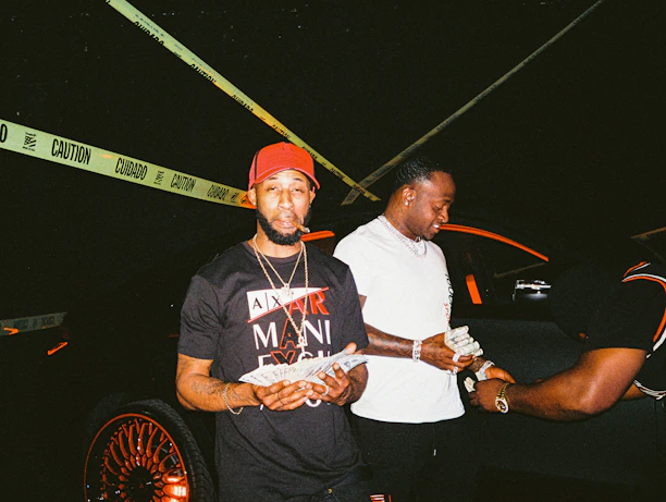 A professional team member handing cash to a satisfied customer beside a junk car.