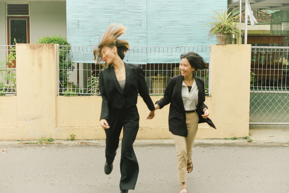 man in black suit jacket and woman in black blazer walking on sidewalk during daytime