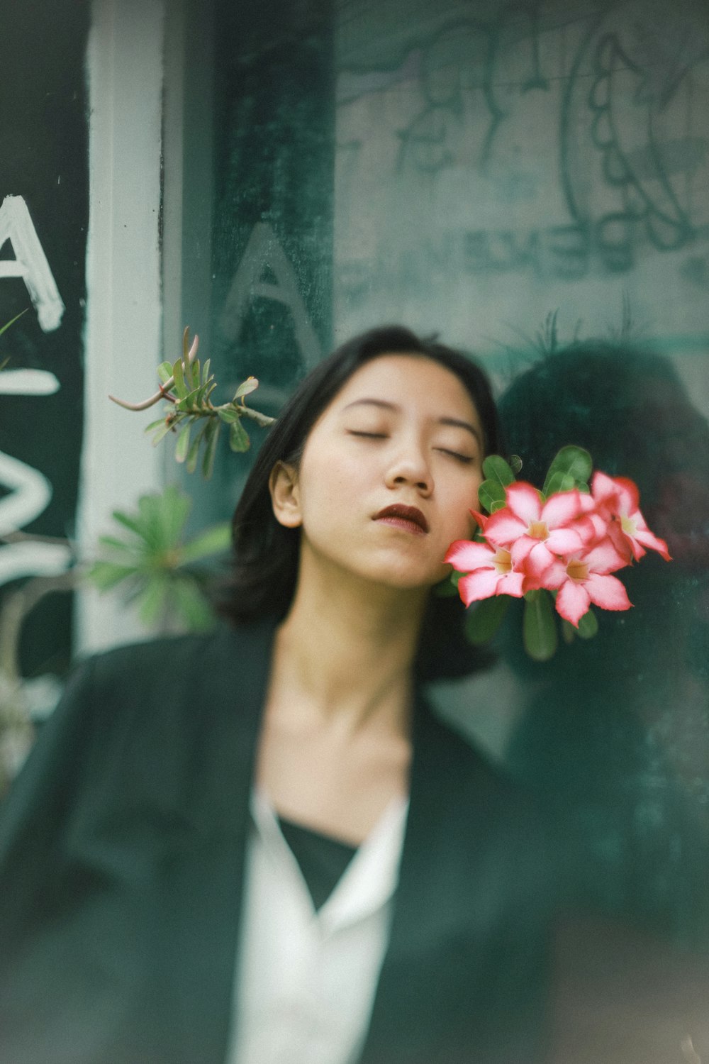 woman in black blazer holding red flower