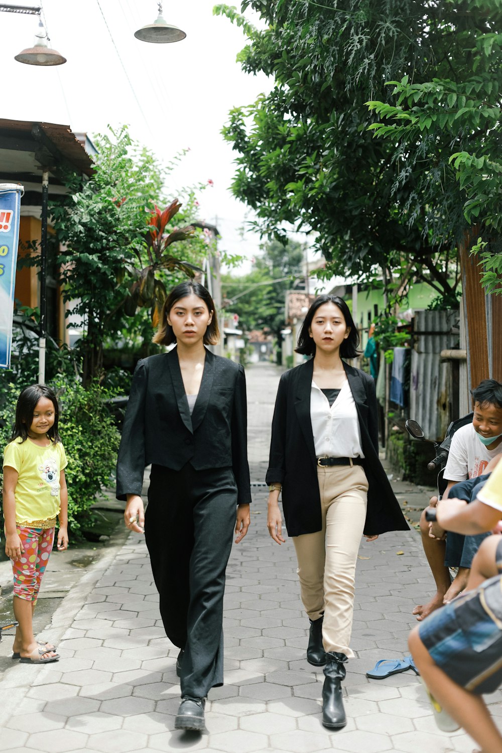Mujer con blazer negro de pie junto a una mujer con blazer blanco