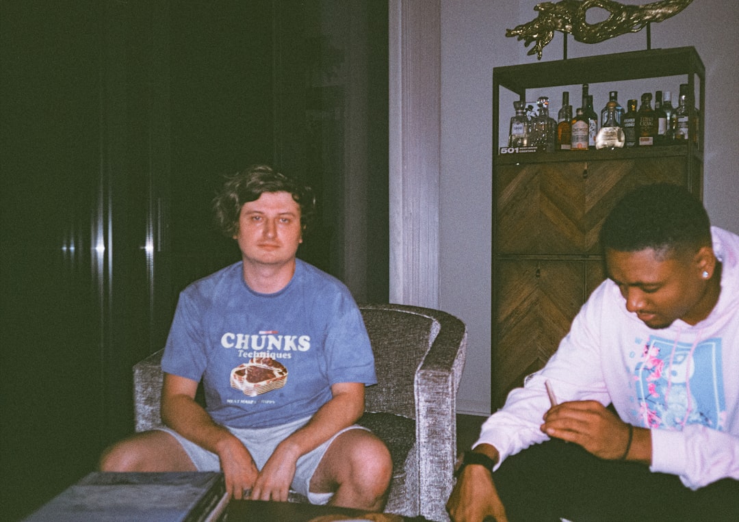 man in blue crew neck t-shirt sitting on brown armchair