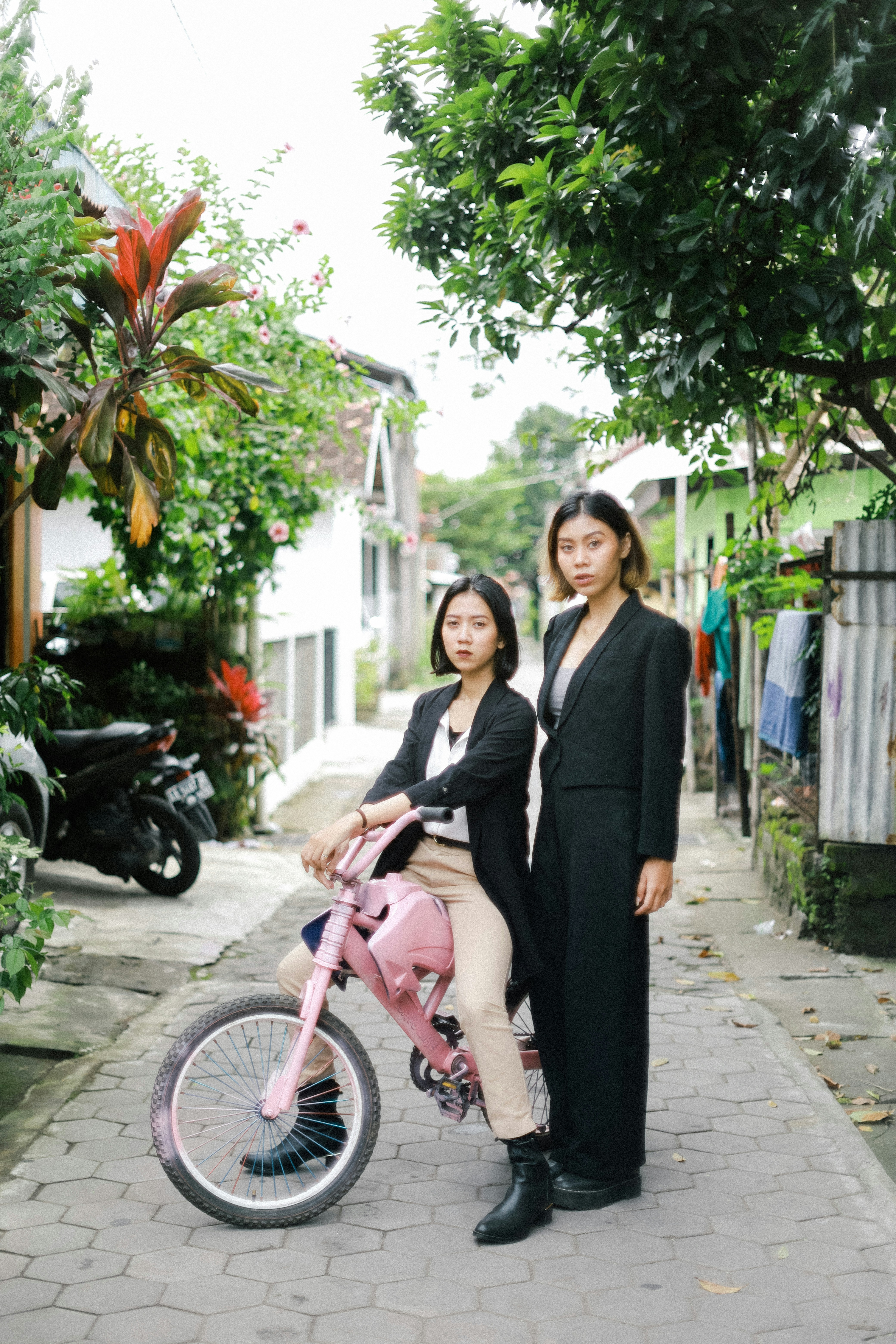 Wanita dalam blazer hitam dan celana merah muda mengendarai sepeda merah muda