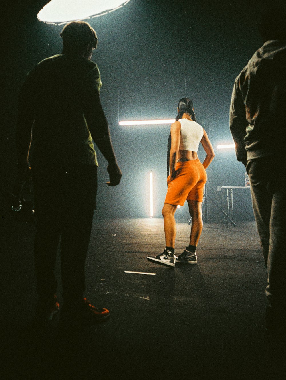 man in black jacket and black pants standing beside woman in orange dress