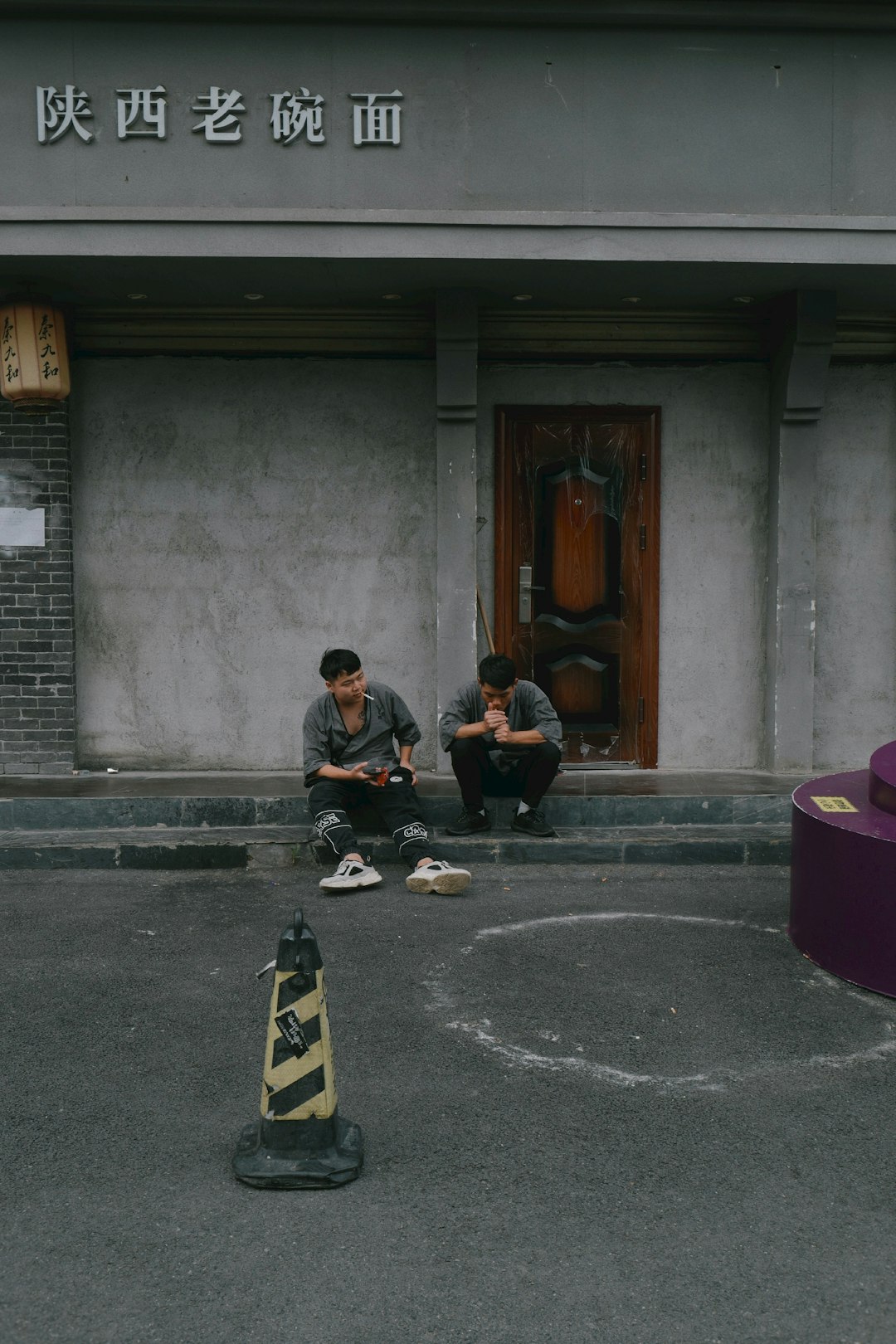 man in black jacket sitting on concrete floor