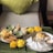 A beautifully arranged platter of Indian snacks and appetizers is displayed, featuring samosas, dhokla, and chutneys. Accompanying these dishes are decorative marigold flowers, enhancing the presentation. The setting is cozy, with a plush cushion in the background.
