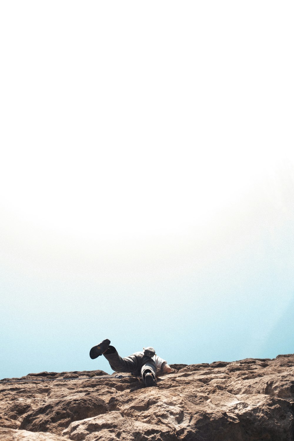 Silueta del hombre sentado en la formación rocosa durante el día