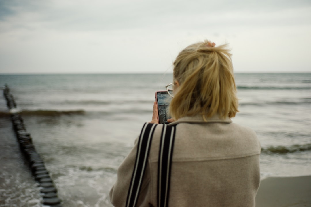 woman in gray hoodie standing on seashore during daytime