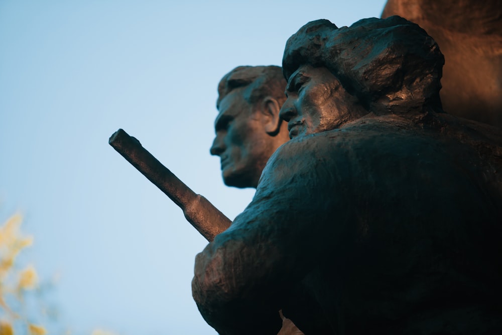 man holding stick statue during daytime