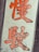 Large orange Chinese characters are displayed on a white vertical rectangular sign against a metal background. The characters appear bold and stylized.