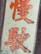 Large orange Chinese characters are displayed on a white vertical rectangular sign against a metal background. The characters appear bold and stylized.