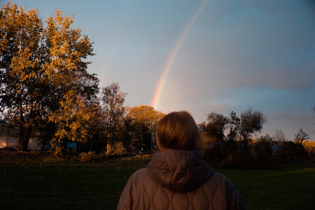 woman in brown hoodie standing on green grass field during daytime