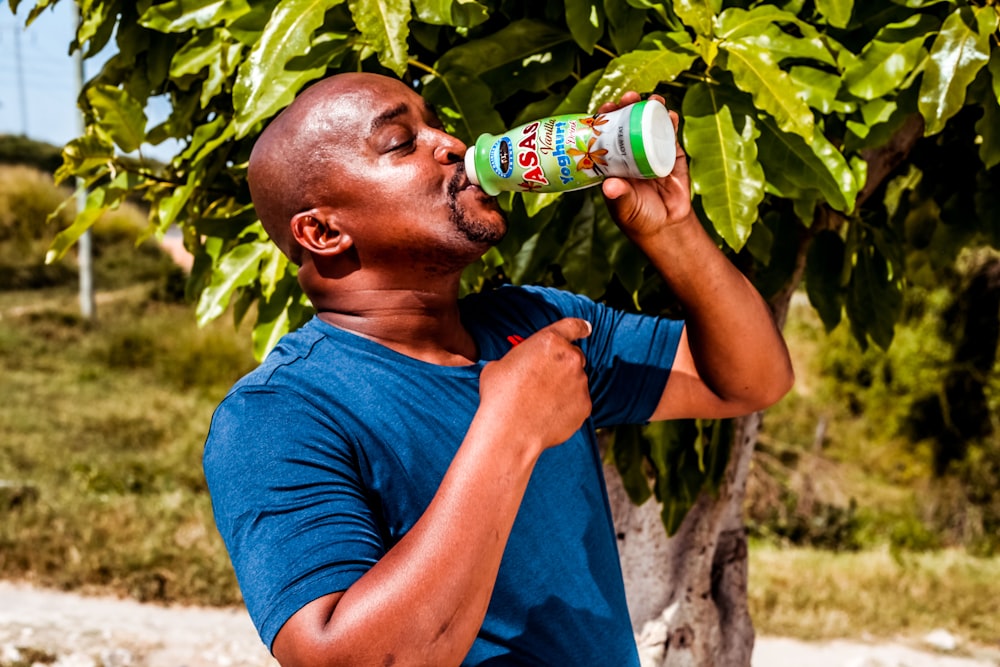 man in blue crew neck t-shirt drinking from bottle