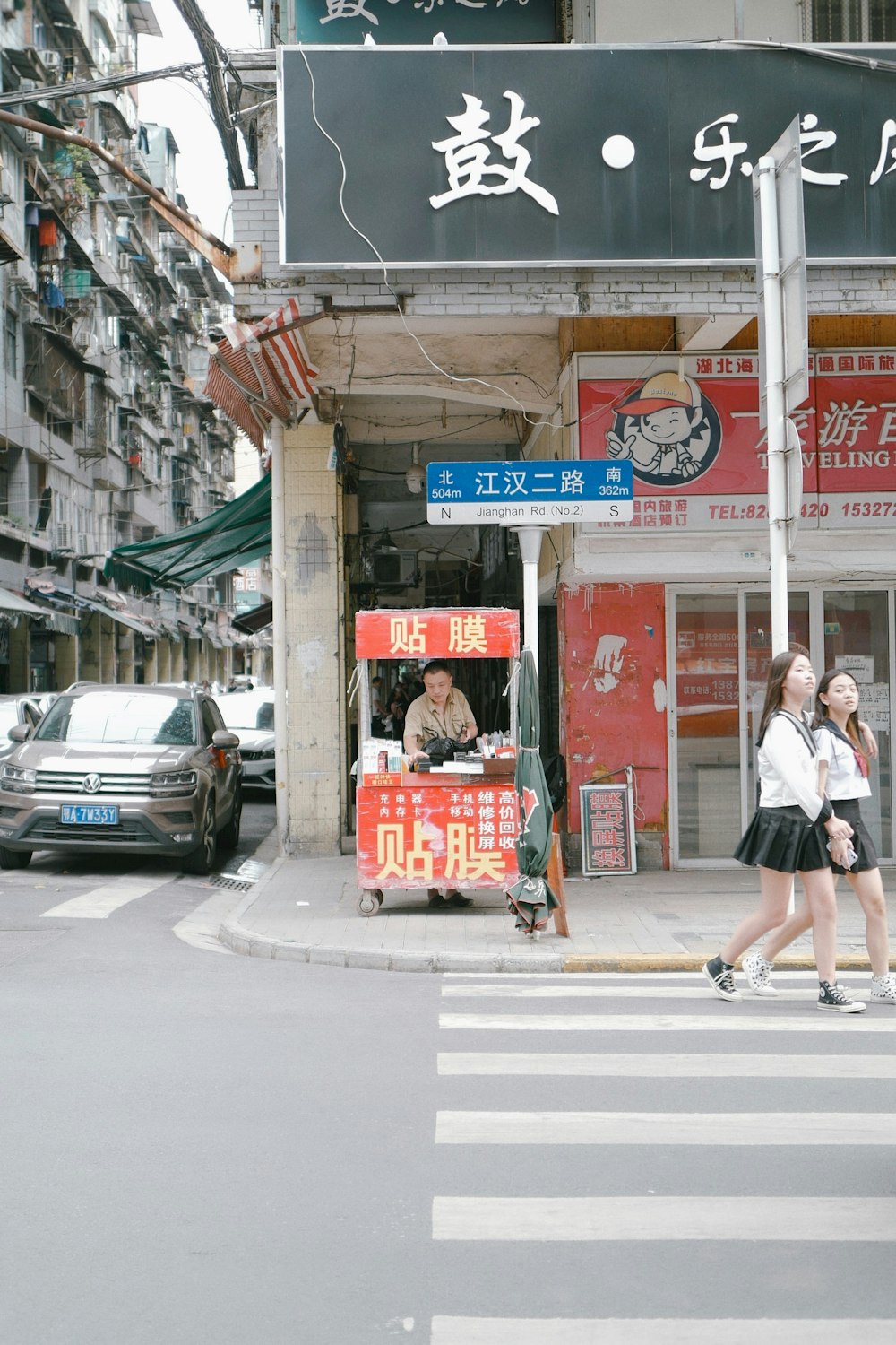 woman in white shirt and black skirt walking on sidewalk during daytime