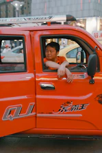 Close-up of a confident driver checking delivery documents beside a bright orange-accented truck.