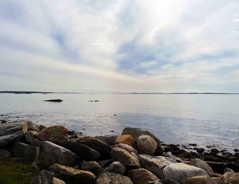 brown rocks on sea shore under cloudy sky during daytime