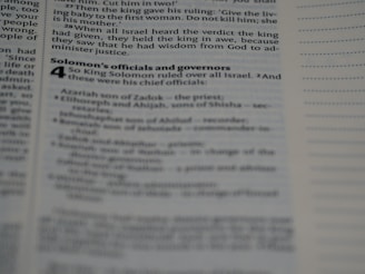 A page from a book containing biblical text is open, displaying text in a column format with black print on white paper. The text includes sections from the story of King Solomon, with headings and subheadings visible.