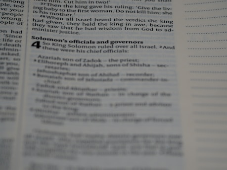 A page from a book containing biblical text is open, displaying text in a column format with black print on white paper. The text includes sections from the story of King Solomon, with headings and subheadings visible.