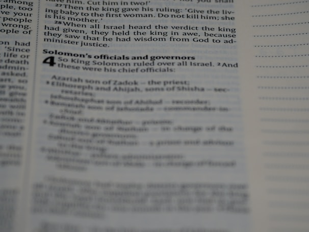 A page from a book containing biblical text is open, displaying text in a column format with black print on white paper. The text includes sections from the story of King Solomon, with headings and subheadings visible.