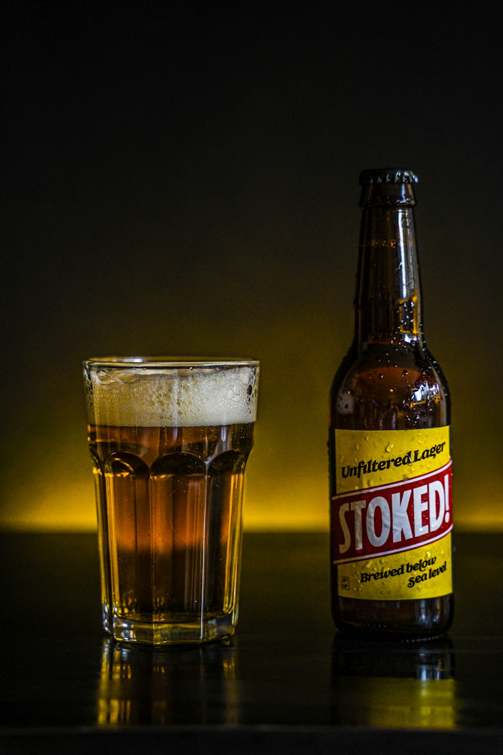 brown glass bottle beside clear drinking glass