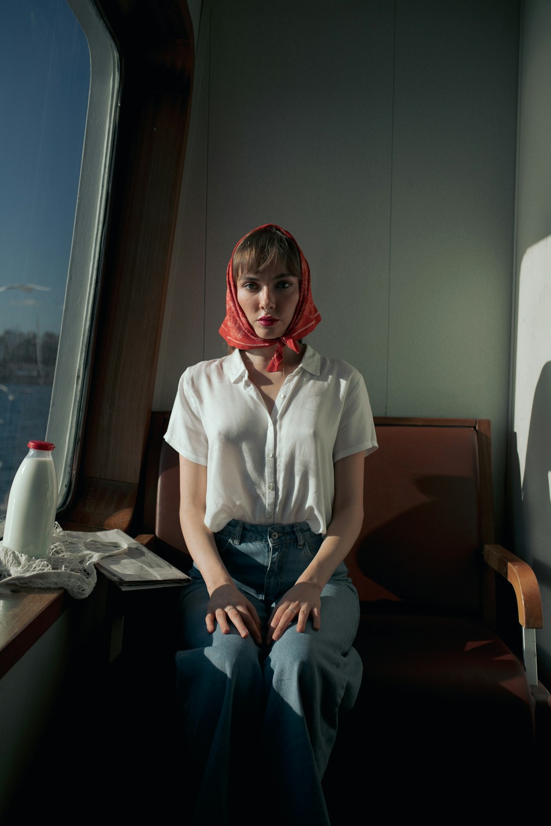 woman in white button up shirt and blue denim jeans sitting on brown wooden chair