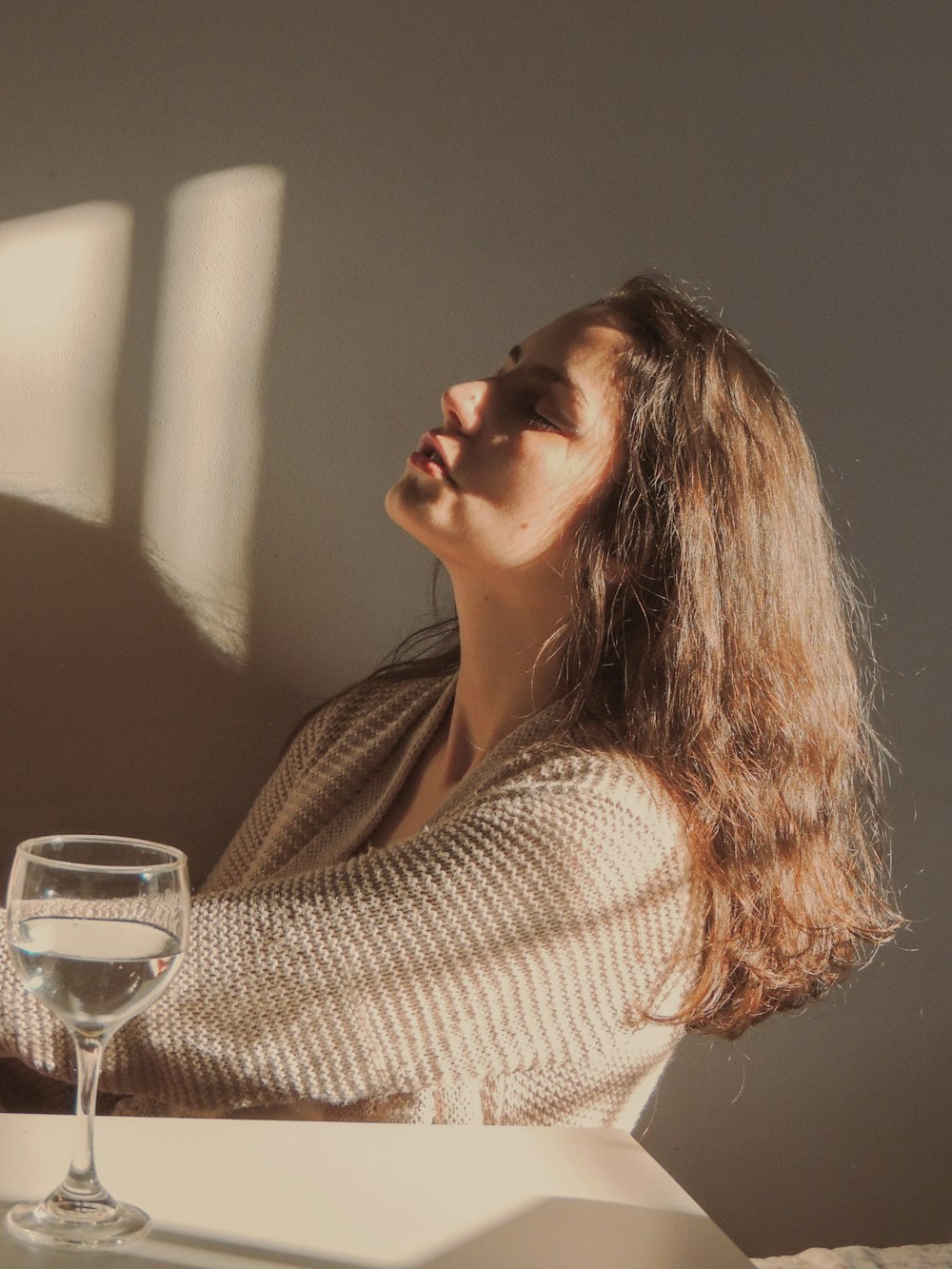 woman in white knit sweater holding clear wine glass