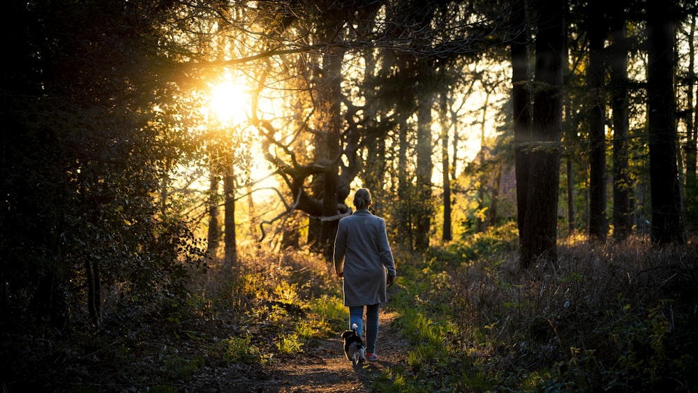 Frau im grauen Kittel geht tagsüber im Wald spazieren
