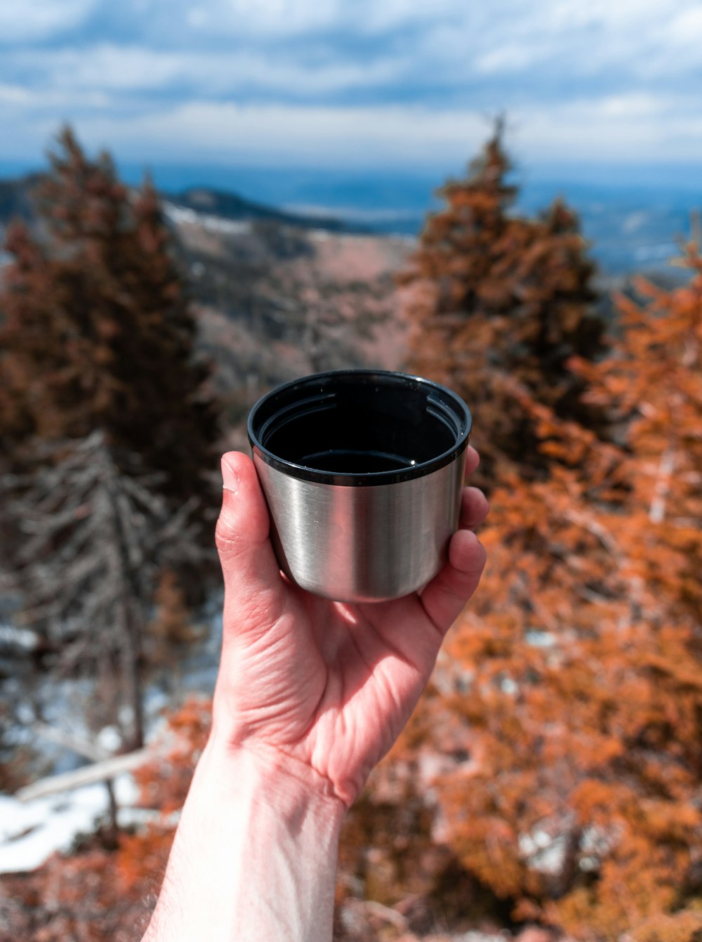 person holding black and silver cup