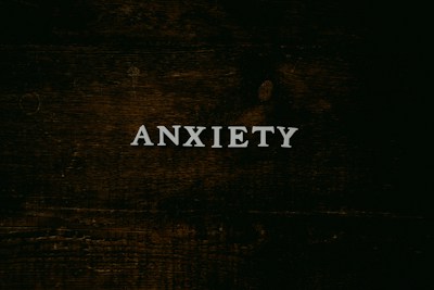 A dark wooden textured background with the word 'ANXIETY' in white capital letters centered prominently.