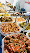 Colorful array of Indian pickles displayed in traditional glass jars on a wooden table.