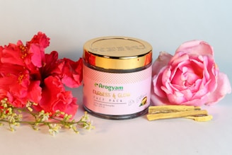 a pink flower next to a jar of honey