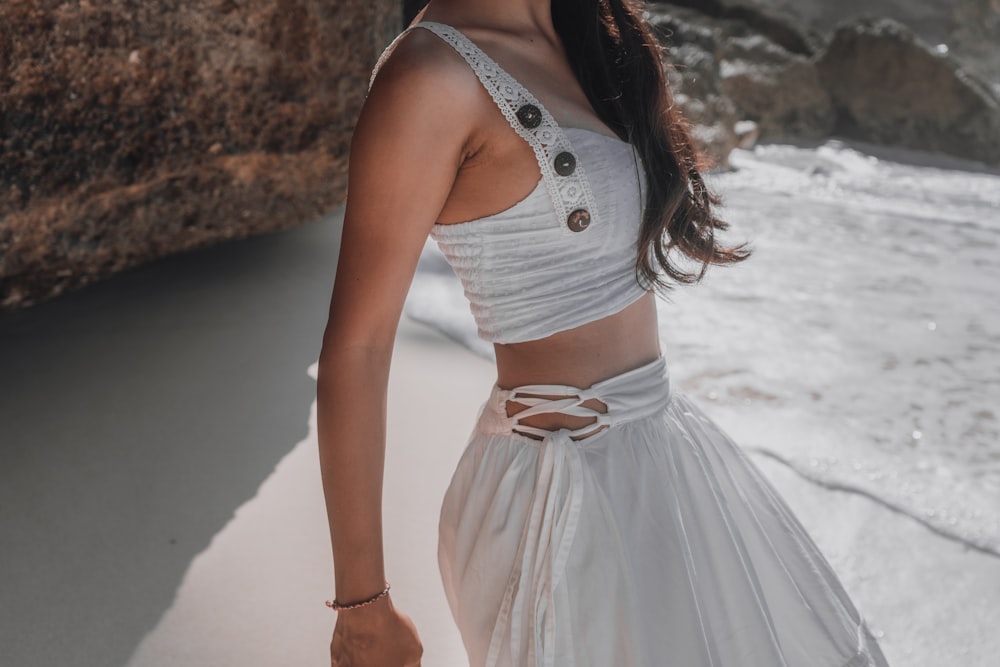 woman in white sleeveless dress standing on white sand during daytime