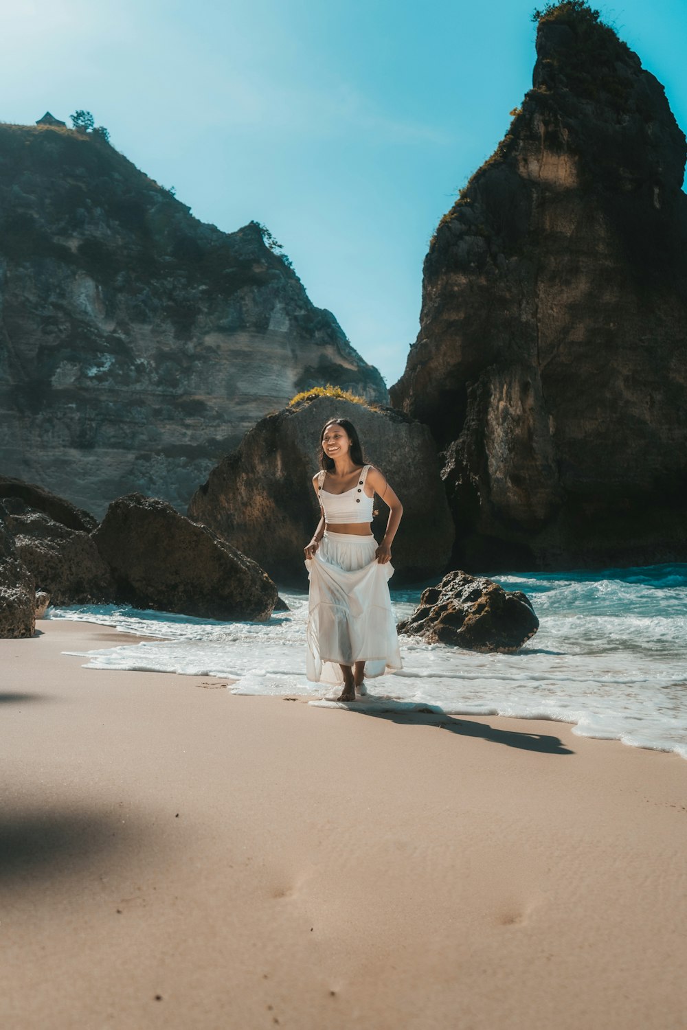 donna in abito bianco in piedi sulla spiaggia durante il giorno