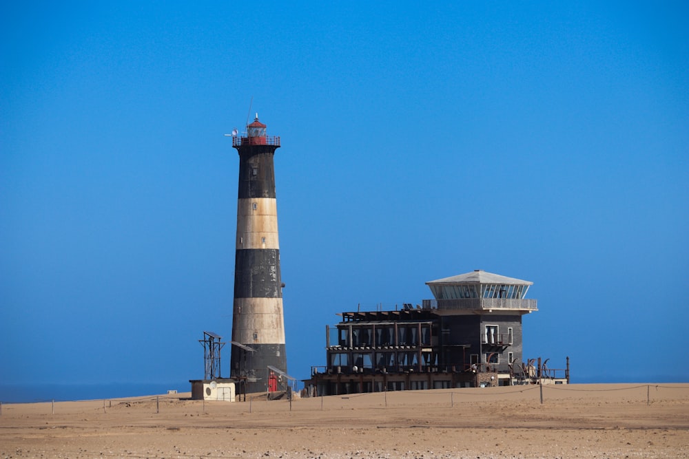 white and black concrete building near brown sand under blue sky during daytime