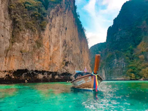 An outrigger boat gliding smoothly over crystal-clear turquoise waters with limestone cliffs in the background under a sunny sky