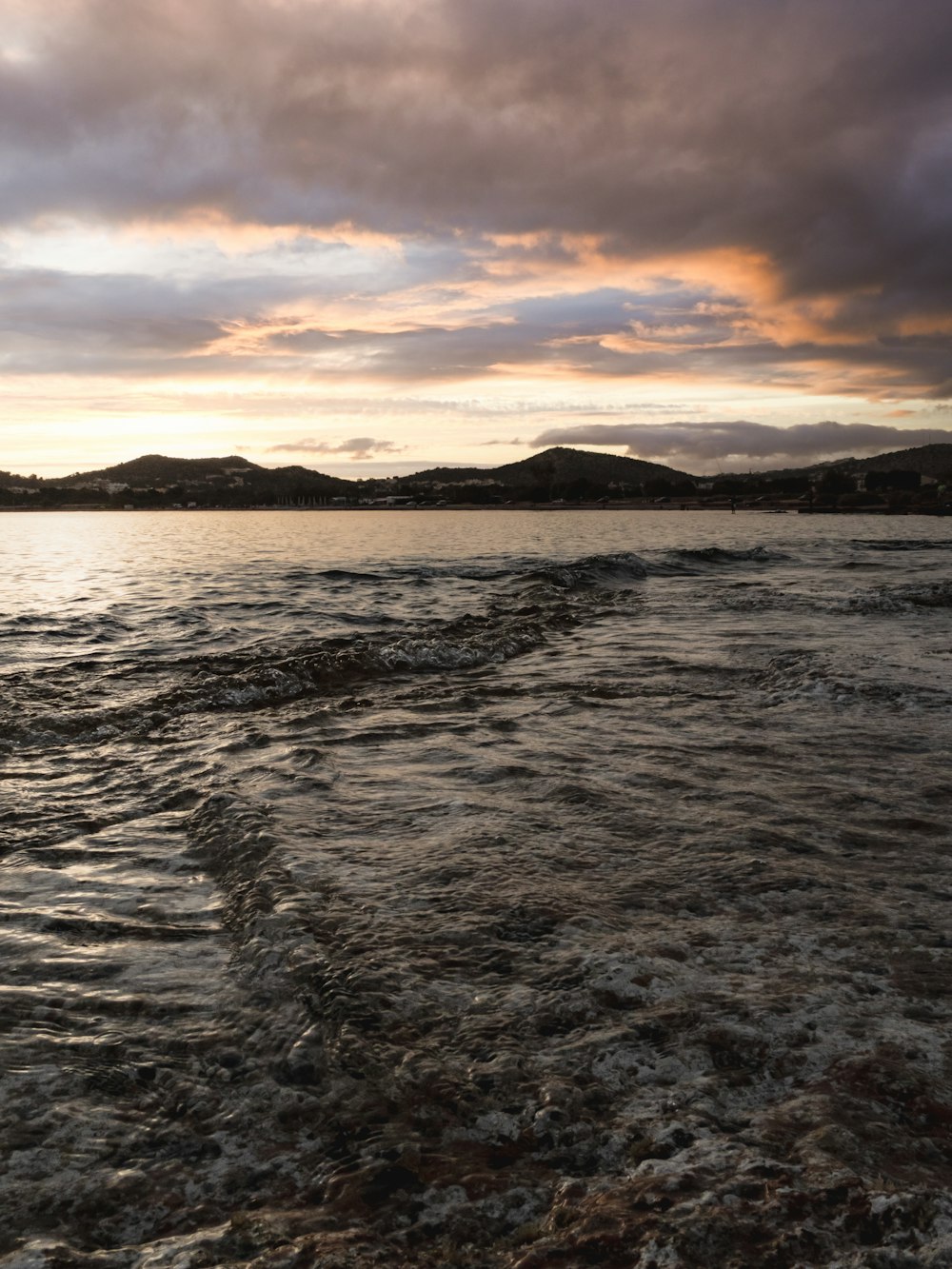 body of water under cloudy sky during sunset