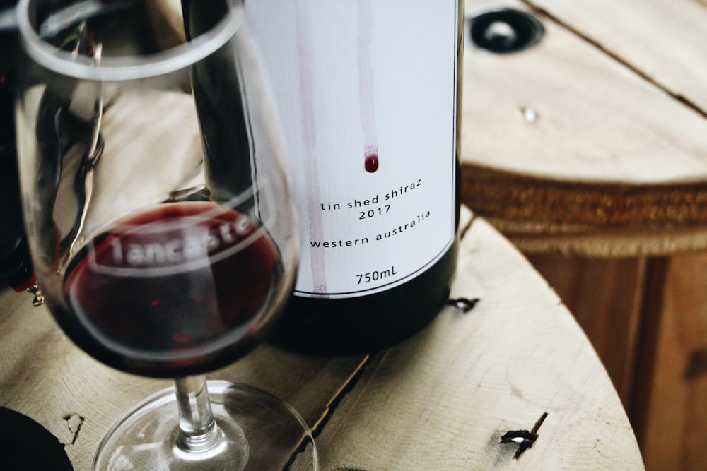 white labeled bottle beside wine glass