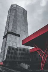 A sleek construction site showcasing a modern building framed by steel and glass under a moody sky.
