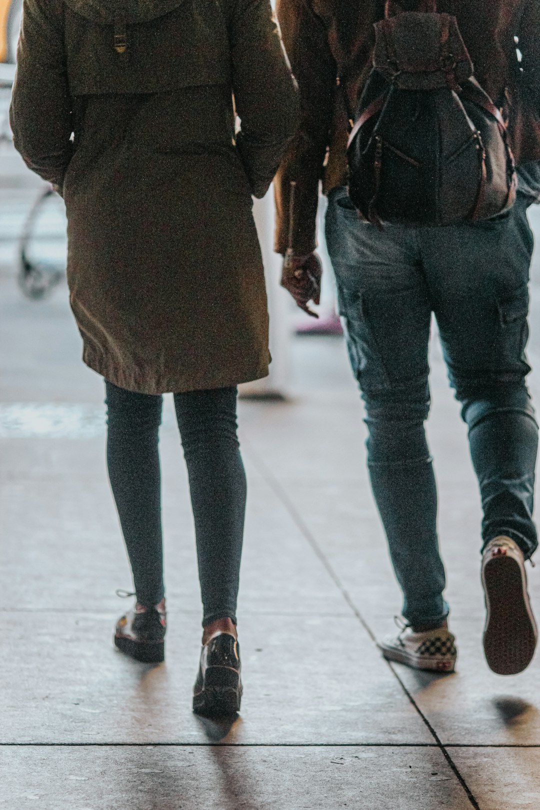 woman in black pants and brown coat standing on white floor tiles