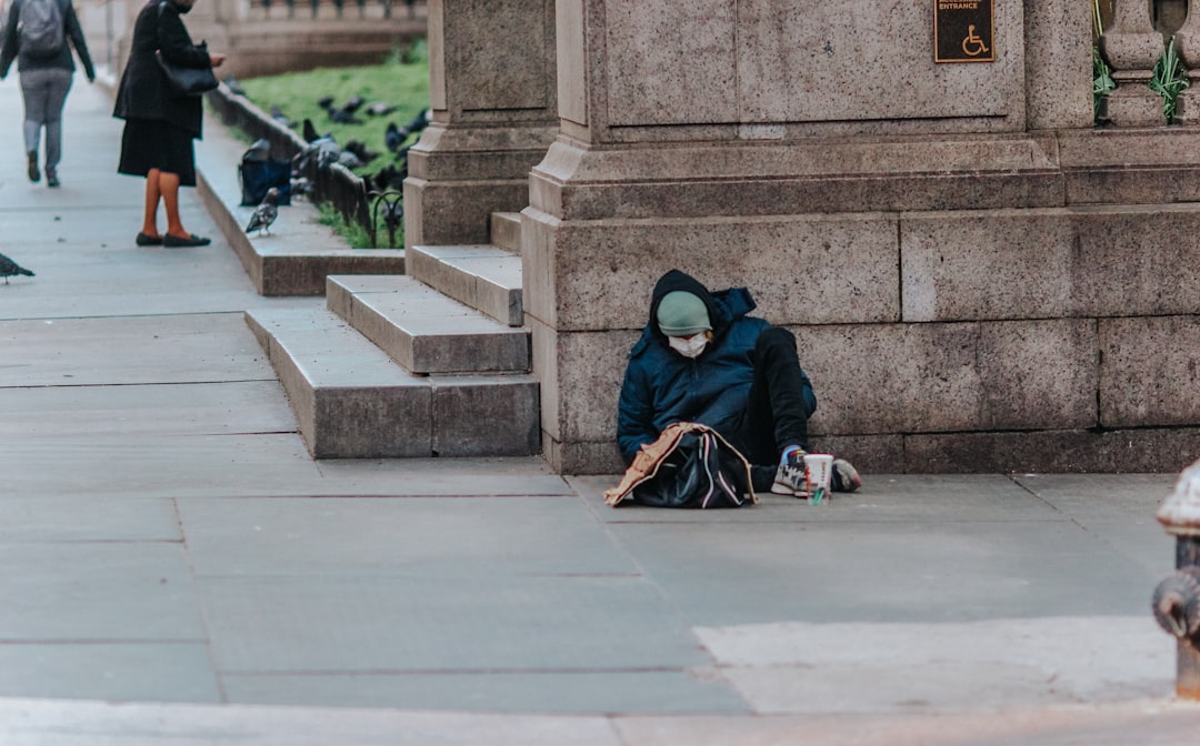 man in blue jacket sitting on concrete stairs