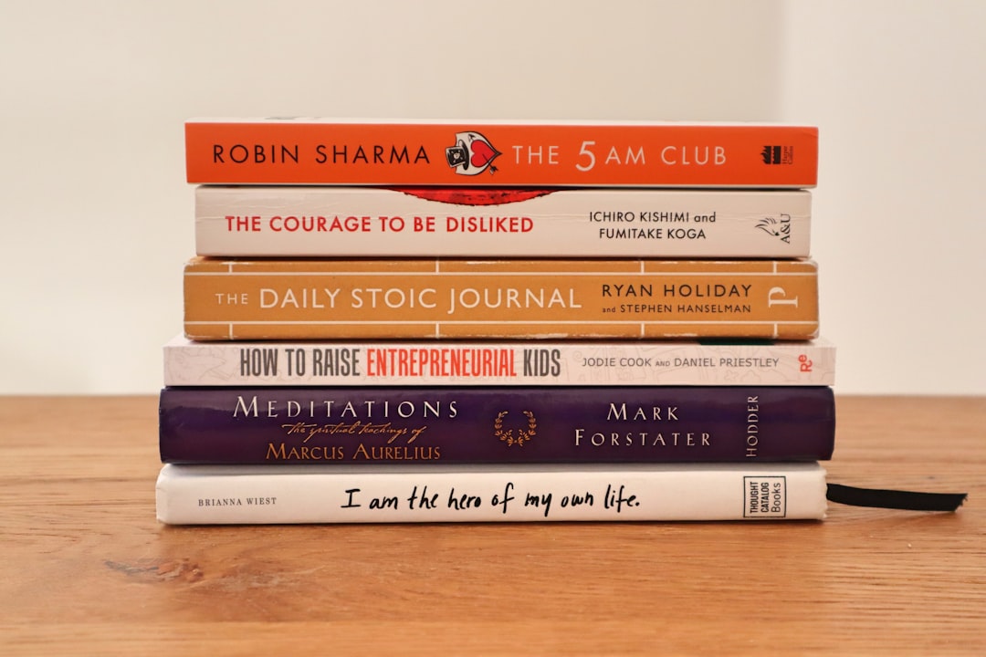 assorted books on brown wooden table, Business book stack containing: Robin Sharma