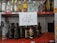 A shelf with various brands of alcoholic beverages, including bottles of vodka, rum, tequila, and whiskey. In the center, a handwritten sign reads 'LEY SECA' indicating a dry law or prohibition.