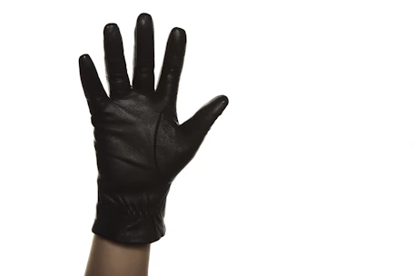 Close-up of a hand wearing a durable leather glove against a rustic wooden background.