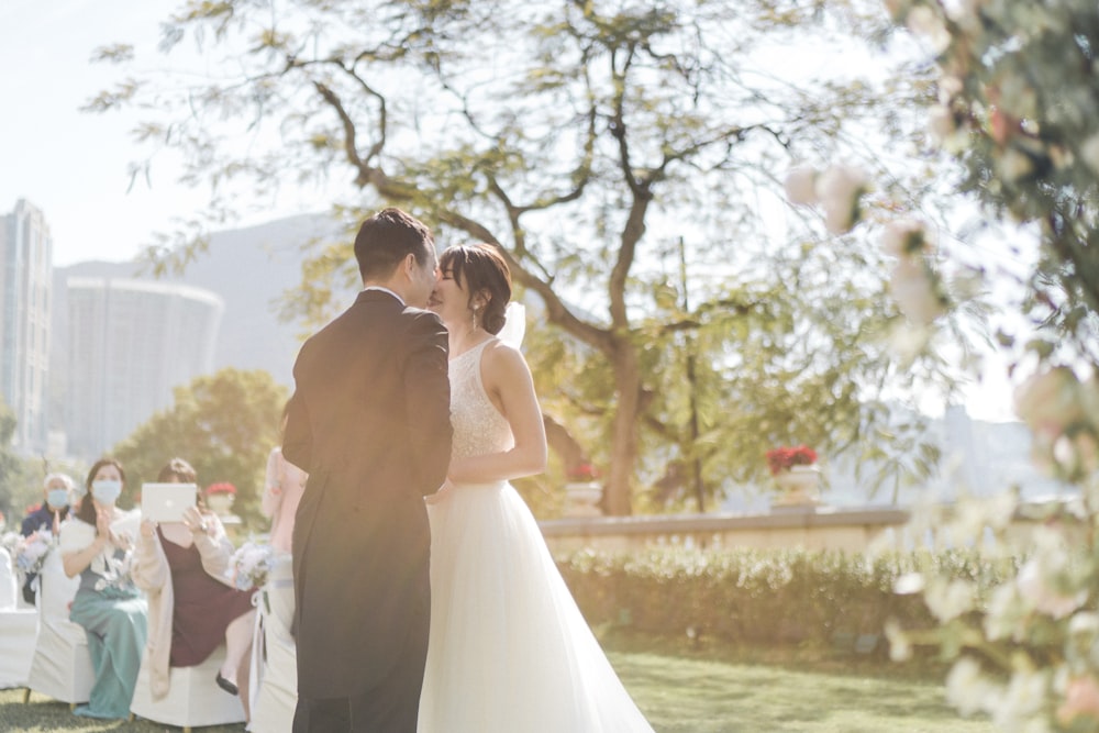 man and woman kissing under white tree during daytime