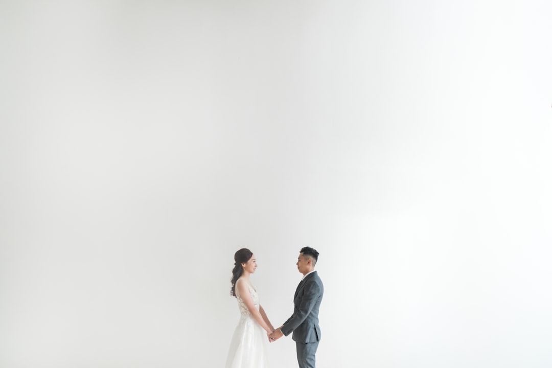 man in black suit kissing woman in white wedding dress