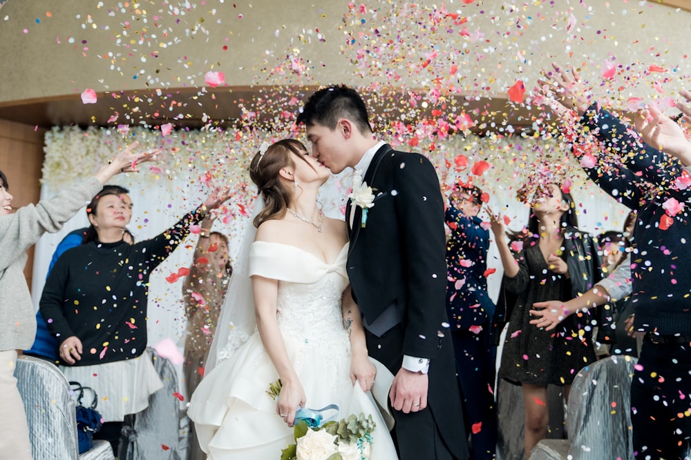 man in black suit kissing woman in white wedding dress