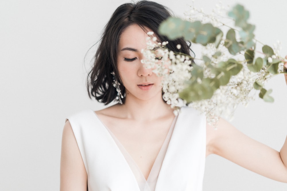 woman in white sleeveless top with white flower on ear