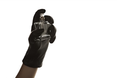 Minimalist photo of a hand holding a small Essence House perfume decant against a bright, clean white wall