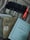 A collection of books and writing tools on a surface, including two visible book covers with text in a non-English script, and a set of pens neatly arranged in a fabric holder. The surrounding fabric has a soft, muted color.