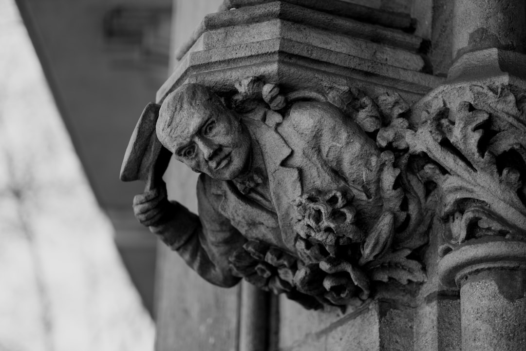 grayscale photo of man holding flower statue