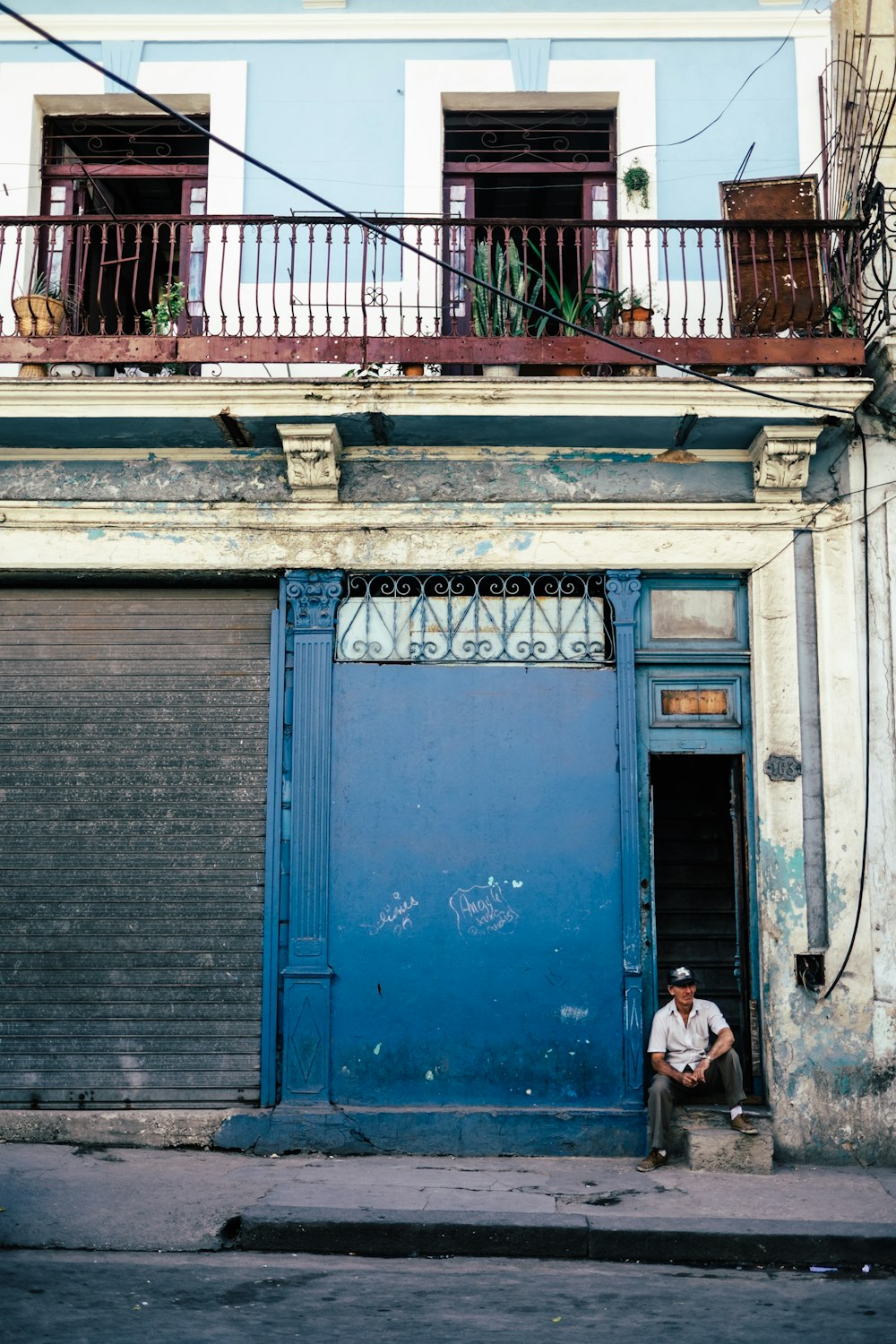 woman in white shirt sitting on blue wooden door during daytime